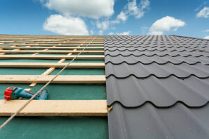 House under construction.Roof with metal tile,screwdriver and roofing iron